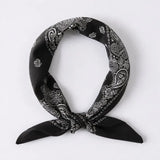 A black bandana scarf with a white paisley pattern, tied in a knot and displayed against a light gray background.
