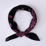 A black bandana scarf with a pink paisley pattern, tied in a knot and displayed on a light gray background.