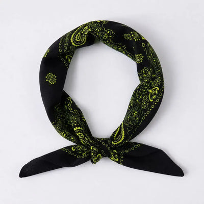 A black bandana scarf with a bright lime yellow paisley pattern, tied in a loop with the ends knotted, shown on a plain light gray background.