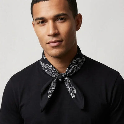 Man wearing a black shirt with a patterned bandana around his neck against a plain background