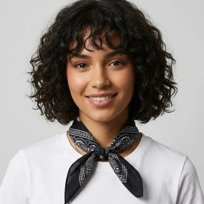 Woman wearing a black bandana around her neck against a plain background